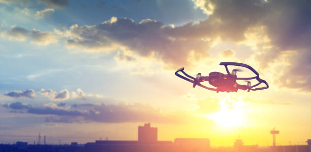 istock Silhouette drone flying overhead in cloudy sunset city sky. 1412565932