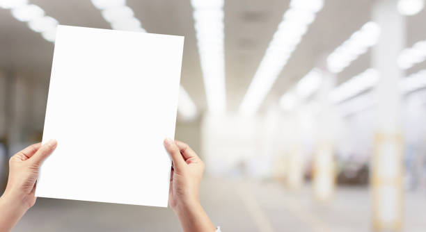 Hands holding white empty paper at factory production background.