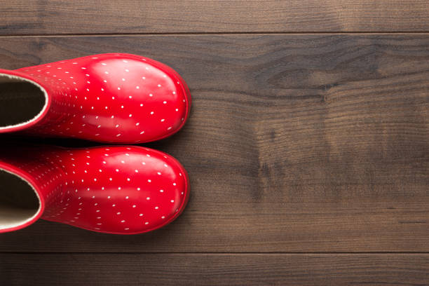 new red children's stylish gumboots on wooden floor