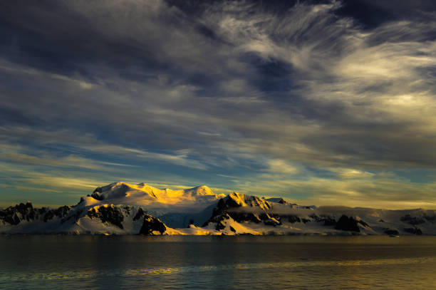 Dark sky with mix of clouds forms a natural space for copy. The Dusk light makes the mountains glitter. There is a dark cloud bank on the mountains.