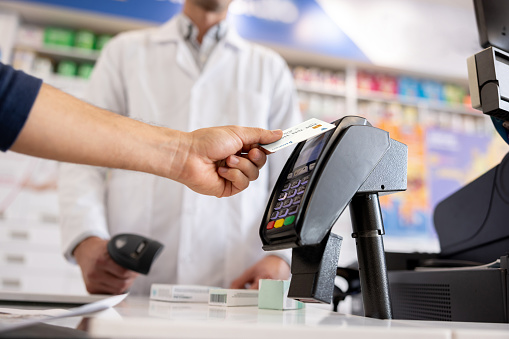 Close-up on a man making a contactless payment at the pharmacy using his credit card