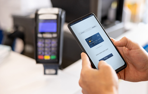 Close-up on a customer making a contactless payment with their cell phone at the pharmacy