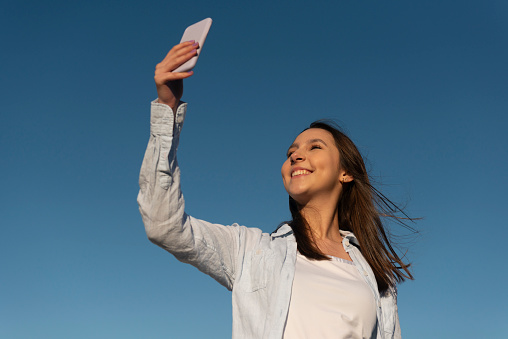 Image with a young woman taking a selfie and enjoying the outdoors