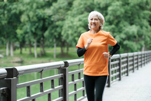 Athletic Senior woman running outdoor jogging in park. stock photo