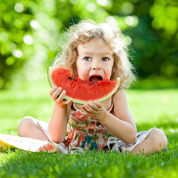 istock Child eating watermelon outside at park 141257271