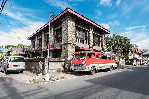 Pagsanjan, Laguna, Philippines - April 2022: An old and restored Spanish-era house with vernacular Filipino architecture. A mini-bus is parked on the curb.