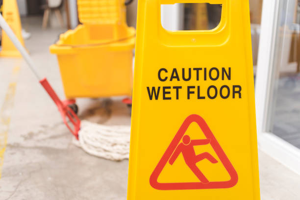 istock A Caution Wet Floor sign placed to warn passersby while wiping a wet concrete floor with a string mop. 1412575751