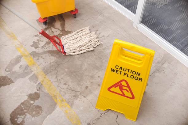 istock A Caution Wet Floor sign placed to warn passersby while wiping a wet concrete floor with a string mop. 1412575752