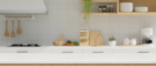 istock Modern white kitchen countertop with copy space over blurred minimal white kitchen in the background. 1412577721
