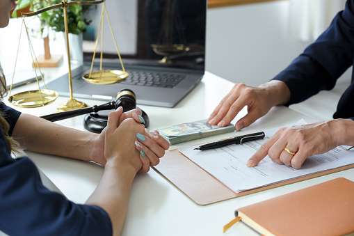 A professional female lawyer having a meeting with her client to sign the agreement contract in the office. cropped image