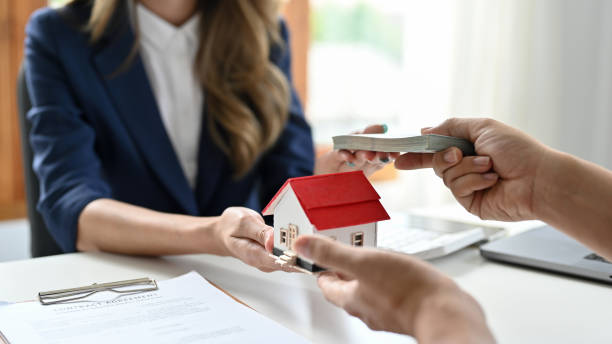 A mortgage broker handling a miniature house to a client