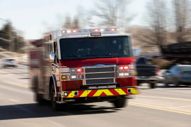 Motion panned view of a fire truck racing with sirens blaring to the scene of an emergency.