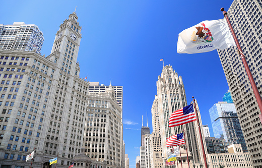 Wrigley Building and Tribune Tower on Michigan Avenue with Illinois flag on the foreground in Chicago