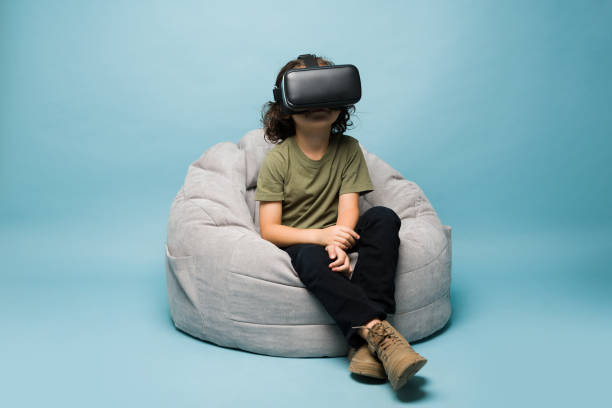 istock Young kid playing virtual reality games with VR glasses 1412583579