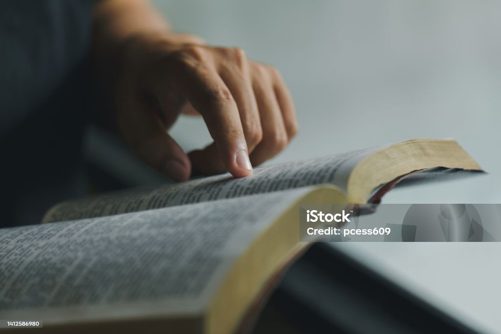 Close-up of Christian man's hands while reading the Bible outside.Sunday readings, Bible education. spirituality and religion concept. Reading a book. Preacher Stock Photo