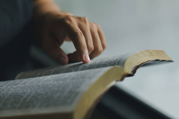 close-up das mãos do homem cristão enquanto lia a bíblia lá fora. leituras de domingo, educação bíblica. espiritualidade e conceito de religião. lendo um livro. - holy book - fotografias e filmes do acervo