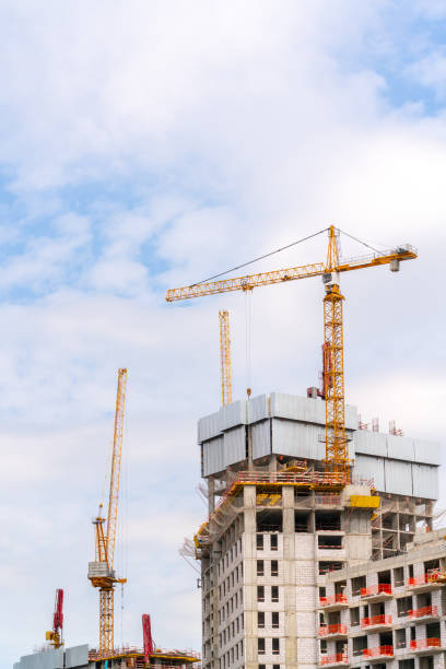 Construction cranes near the facade of a house under construction. stock photo