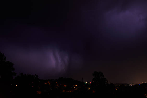 istock Lightning discharges in the stormy sky under dark rain clouds at night 1412594415