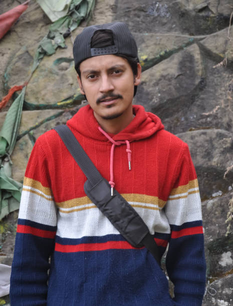 istock Front view of a young guy with wearing cap backwards, looking at camera while standing against rock 1412597468