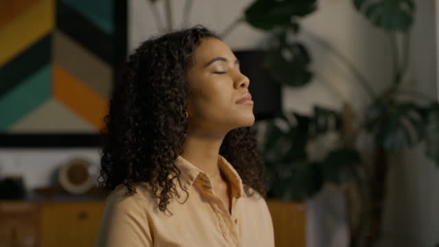 A woman meditating and doing breathing exercise at home. Calm and carefree young female relaxing and feeling serene enjoying the moment. A life of mindfulness and mental health wellness