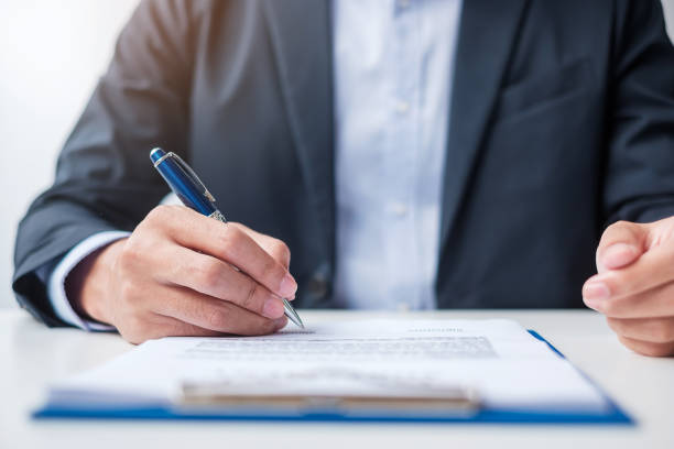 istock man signing on contract documents after reading, man holding pen and approve on business report. Contract agreement, law and deal concepts 1412604272