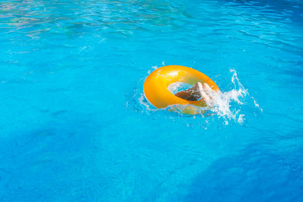 l’enfant saute dans un cercle gonflable dans la piscine. seules les jambes du bébé sont visibles en cercle en vol - swimming pool child swimming buoy photos et images de collection