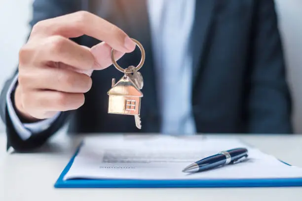 Photo of man holding home key during signing home contract documents. Contract agreement, real estate,  buy and sale and insurance concepts