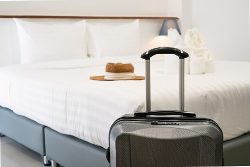 Close up of luggage in hotel room. Comfortable hotel bedroom in cozy style. Holiday, vacation, business trip concept.