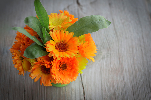 a bouquet of calendula on a wooden table top view with a copy of the space.