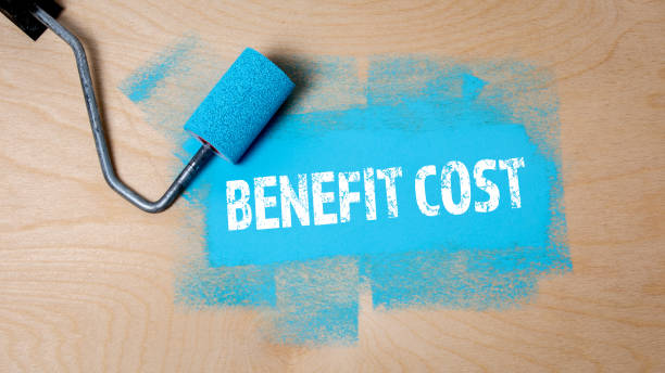 istock Benefit Cost. Paint roller with blue paint on a wooden surface 1412609159