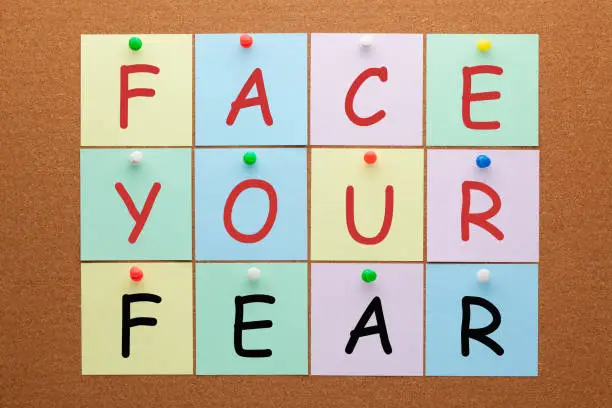 Face your fear text on notes pinned on cork board. Healthy concept