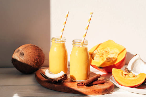 batido de calabaza y coco en botellas con paja. alimentos crudos veganos saludables. closeup - bebida batida fotografías e imágenes de stock