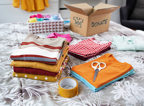 Folded used clothes on the bed and carton box, charity and donation concept