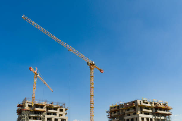 istock Two large yellow industrial cranes operating on an apartment house construction site 1412619384