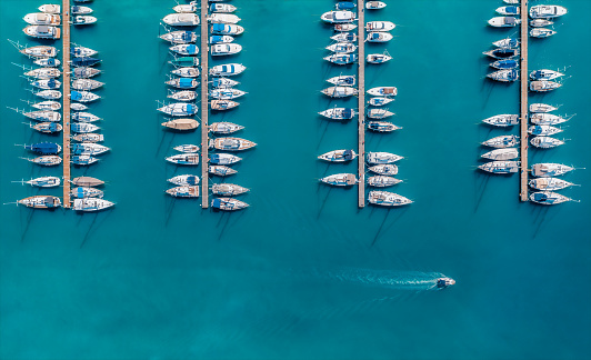 Vista aérea de yates de lujo y lanchas a motor amarradas en un puerto con aguas azules claras en verano. Vista superior desde el dron de veleros y varias lanchas rápidas en el muelle. Pula, Croacia photo