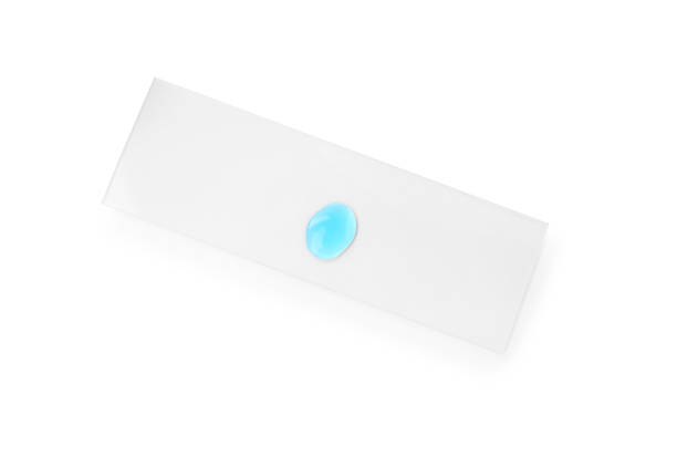 portaobjetos de microscopio con muestra de líquido azul claro aislado en blanco, vista superior - microscope slide fotografías e imágenes de stock