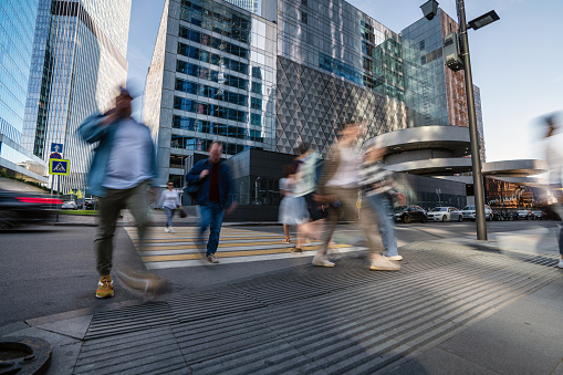 People blurred in motion at the crosswalk at the modern business quarter