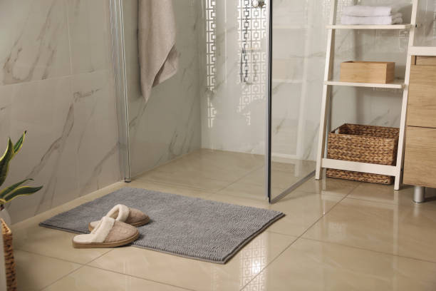 istock Soft grey bath mat and slippers on floor in bathroom 1412621800