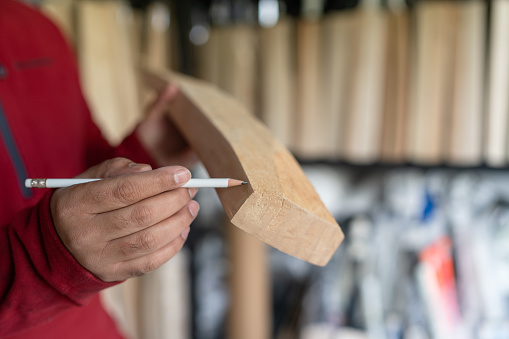 Business owner marking cricket bat to cut it for special order.