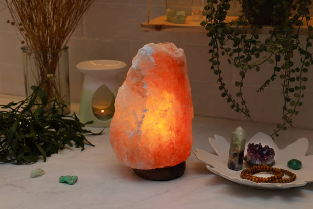 istock Himalayan salt lamp, crystals and oil diffuser on white table near brick wall 1412621911