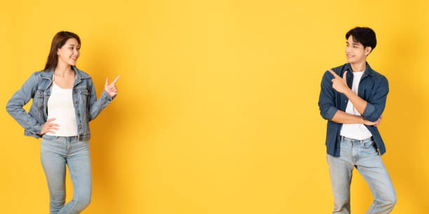 istock Two Young good looking asian couple using isolated on yellow background presenting to copy space 1412622603