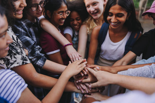 istock Group of multicultural teenagers putting their hands together in unity 1412626408