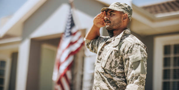 Patriotic young soldier saluting outdoors stock photo
