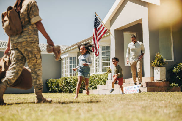 Military mom being welcomed by her family at home Military mom receiving a warm welcome from her husband and kids. American servicewoman reuniting with her family after serving in the army. Female soldier returning home from deployment. patriotic man stock pictures, royalty-free photos & images