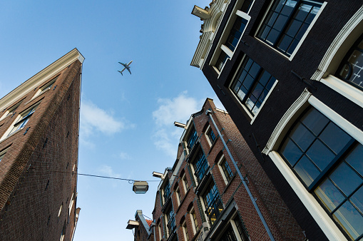Airplane flying low over typical Amsterdam brick houses