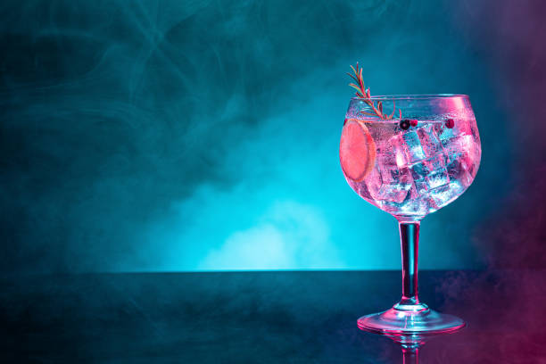 istock Cold gin tonic under pink and blue light illumination on smoky background with copy space. 1412629983