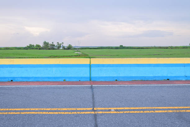 A vibrant red racing helmet rests on a yellow wooden box marked with the number '1', symbolizing first place or the top position. The image is set against a blurred background of a go-kart track, with colorful tires and racing infrastructure visible, capturing the essence of competitive motorsport.
