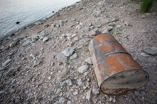 Risty steel barrel rusting at river shore