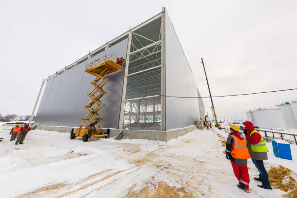winter industrial building process at cloudy day workers mounting sandwich panels winter industrial building process with scissor lift at cloudy day in Tula, Russia - February 5, 2013 sandwich panel photos stock pictures, royalty-free photos & images