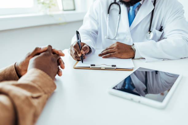 istock Doctor writing application form while consulting male patient in the office. 1412633615